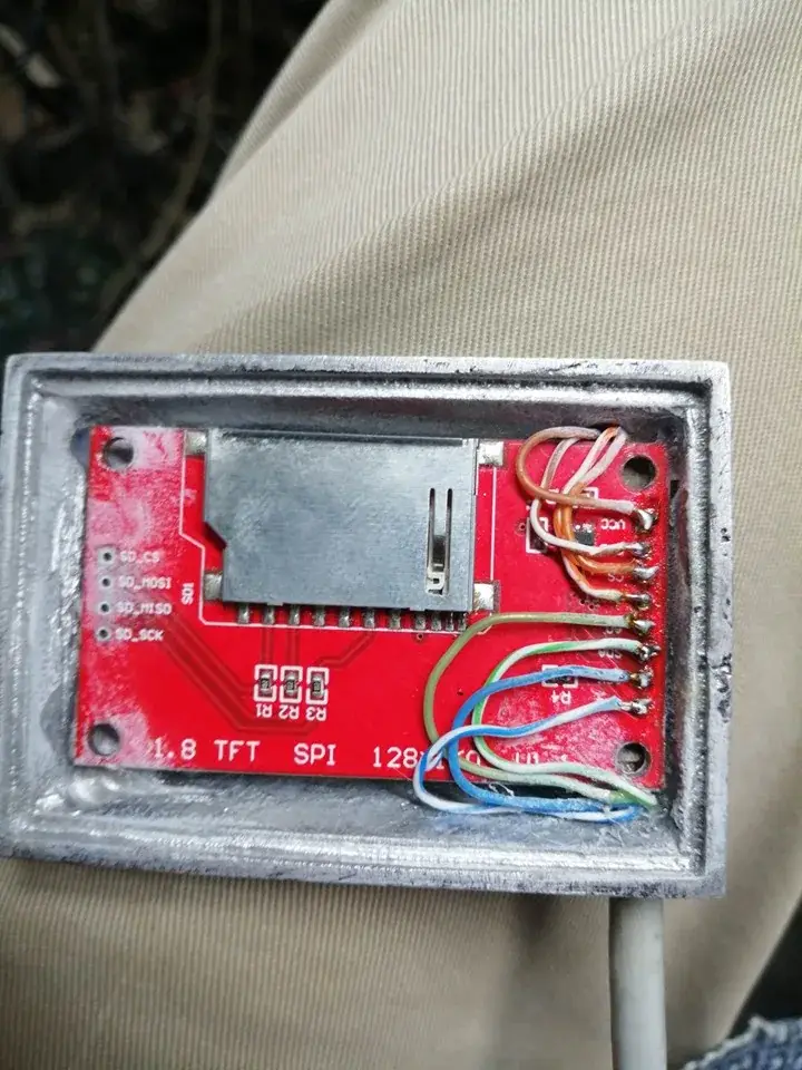 Parte trasera de la carcasa de aluminio de la pantalla con la placa roja del TFT de 1,8 pulgadas dentro, soldada a seis cables de colores por su hilera de pines
